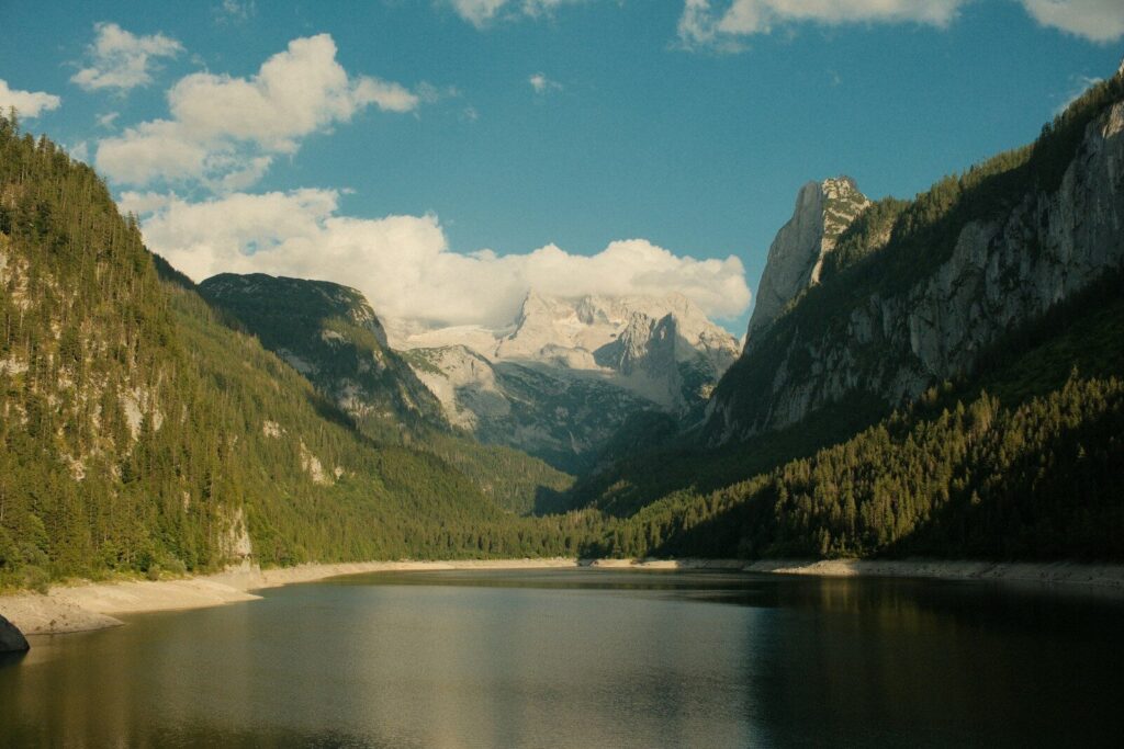 Lake surrounded by forested mountains under a blue sky