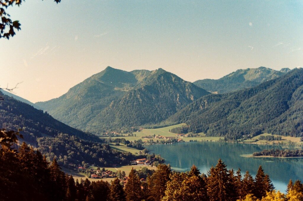 A lake surrounded by green mountains and small villages under a clear sky