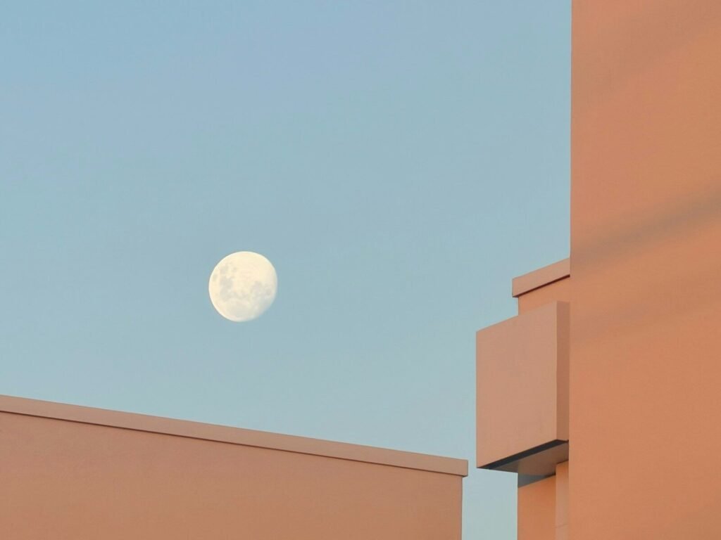 Full moon in a clear blue sky above buildings